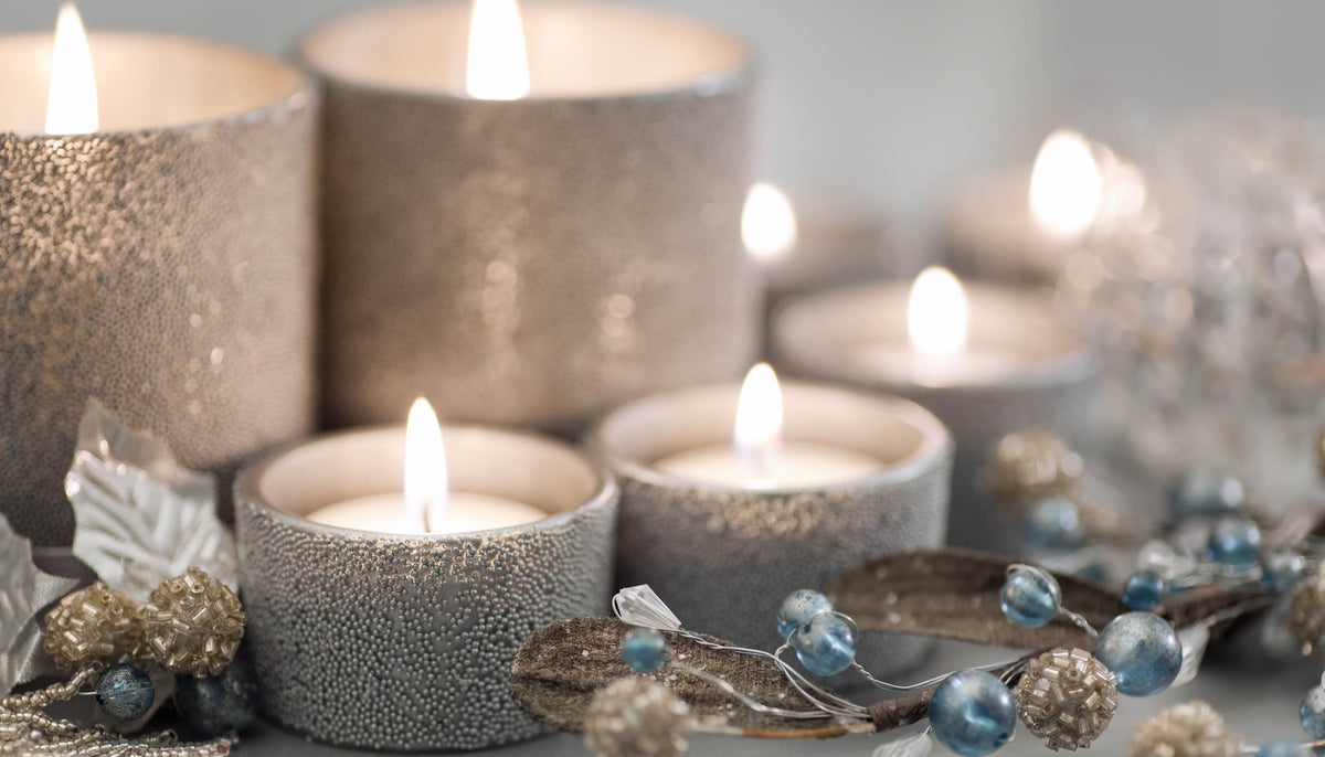 Brandende theelichtjes in zilveren glinsterende houders, tussen decoratieve takjes met blauwe kralen